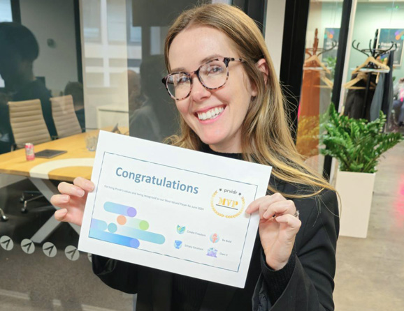 Prvidr employee smiling whilst looking at the camera holding up a Congratulations certificate